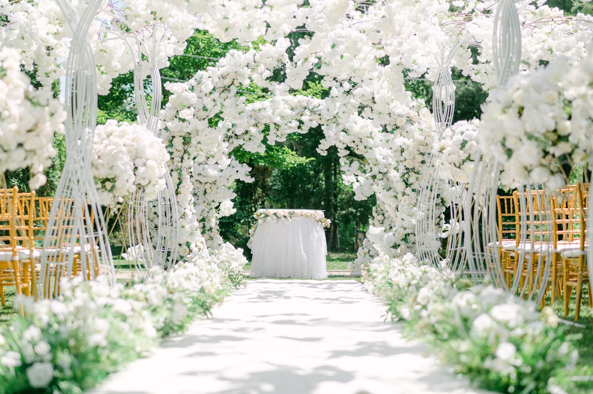 Allée fleurie et arche d'une cérémonie de mariage laïque en extérieur